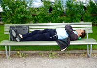 Mann schläft auf Parkbank